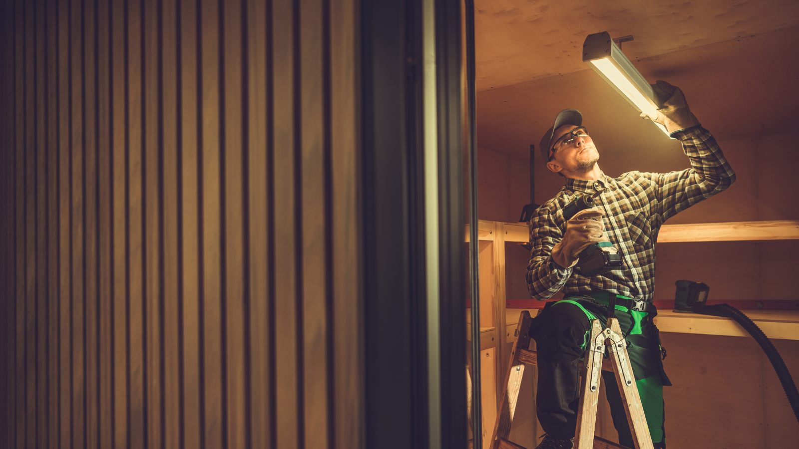 Technikerin bei der Wartung einer LED-Lichtanlage im Innenraum, arbeitet an einer montierten Leuchte.